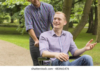 Shot Of A Young Man In A Wheelchair Spending Time In A Park With His Friend