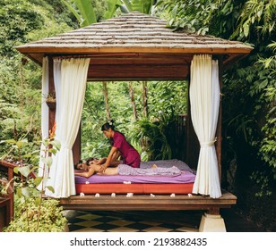 Shot Of Young Man And Woman Receiving Massage At Health Spa In Luxury Resort. Couple At Outdoor Spa Center And Having Body Massage. Outdoor Spa Center At Luxury Resort.