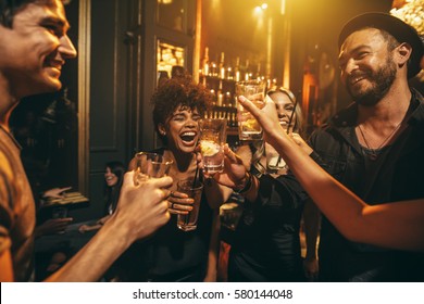 Shot of young men and women enjoying a party. Group of friends having drinks at nightclub.