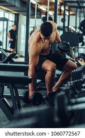 Shot of a young muscular man getting ready to lift dumbbells at a gym - Shutterstock ID 1060772567