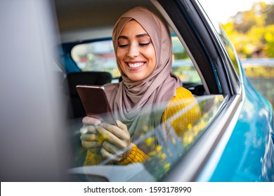 Shot of a young Muslim businesswoman texting on a cellphone in the backseat of a car. Elegant young Muslim businesswoman sitting in car backseat. - Powered by Shutterstock