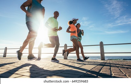 Shot of young runners workout on the sea front path. Running club group running along a seaside promenade. - Powered by Shutterstock