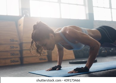 Shot Of Young Woman Doing Push-ups At The Gym. Muscular Female Doing Pushups On Exercise Mat At Gym. Female Exercising On Fitness Mat At Gym.