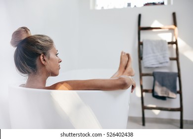 Shot of young woman lying in bathtub and looking away. Beautiful female relaxing in bathtub. - Powered by Shutterstock