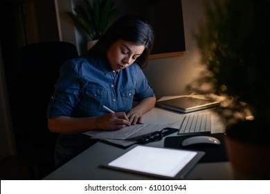 Shot Of A Young Woman Studying For The Exam Late At Night At Home.