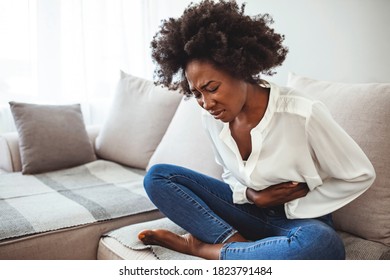 Shot of a young woman suffering from stomach cramps. Woman with abdomen problems in bed, she use hands to massage painful place. Shot of a young woman suffering from stomach cramps at home
