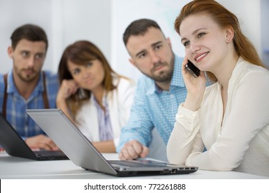 Shot Of A Young Woman Talking On The Phone At The Office During The Meeting Her Male Colleague Looking At Her Angrily Copyspace Distracting Distraction Impolite Angry Judgment Judgmental Look