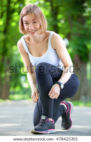 Shot of a young woman tying her laces before a run.