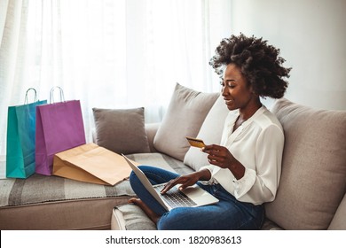 Shot Of A Young Woman Using Her Credit Card To Make An Online Payment At Home. Wireless Retail Therapy. Woman Sitting On Her Sofa At Home And Using Her Tablet For Online Shopping