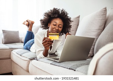 Shot Of A Young Woman Using A Laptop And Credit Card While Relaxing At Home. Keeping The Shopping Mall Close To Home. Shopping Spree Directly From The Sofa 