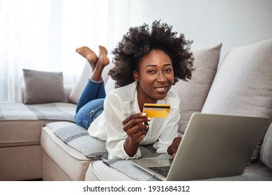 Shot Of A Young Woman Using A Laptop And Credit Card While Relaxing At Home. Keeping The Shopping Mall Close To Home. Shopping Spree Directly From The Sofa 