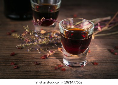 Shots Of Alcoholic Drink On Dark Wooden Background. Herbal Bitter Liquor With Different Natural Ingredients.