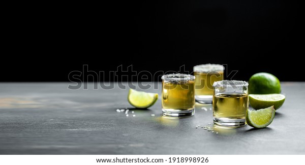 shots of Mexican Gold Tequila with lime and salt on\
stone background. concept luxury drink. Alcoholic drink. place for\
text.