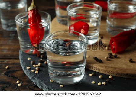 Shots of vodka and pepper on wooden background, close up