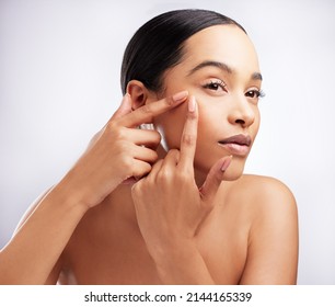 Should I pop it. Studio shot of a beautiful young woman squeezing a pimple on her face against a white background. - Shutterstock ID 2144165339