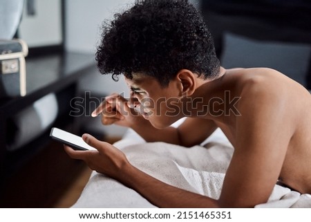 Should I or shouldnt I text her...sent. Shot of a young man using a smartphone while relaxing on his bed at home.