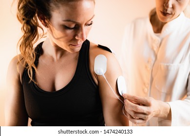 Shoulder Physical Therapy with TENS Electrode Pads, Transcutaneous Electrical Nerve Stimulation. Therapist Positioning Electrodes onto Patient's Shoulder