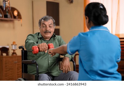 Shoulder shot Indian nurse encouraging to lift dumbbell during to elderly man on wheelchair with disability at home during physiotherapy session - concept of medical counselling and rehabilitation. - Powered by Shutterstock