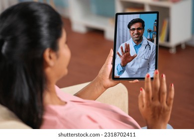 Shoulder shot of indian pregnant woman consulting doctor on video call at home - concept telemedicine, Virtual healthcare and remote consultation. - Powered by Shutterstock