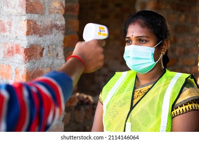 Shoulder Shot Of Man Checking Body Tempreture Of Woman Worker With Medical Face Mask At Workplace - Concept Of Covid19 Precation, Woman Empowerment And Blue Collar Jobs.