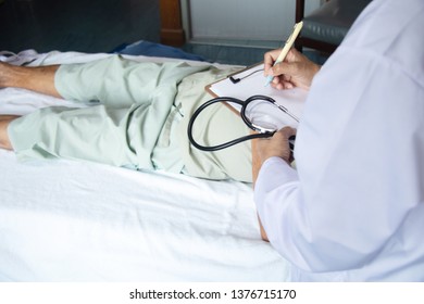 Shoulder View Of Doctor Write The Report On Clipboard With Stethoscope In Hand Examine The Symptom Of Elderly Over 80 S Asian Man Patient After Done Chemotherapy Of Liver Cancer In Hospital Ward Room