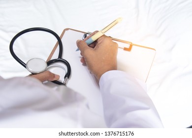 Shoulder View Of Doctor Write The Report On Clipboard With Stethoscope In Hand Examine The Symptom Of Elderly Over 80 S Asian Man Patient After Done Chemotherapy Of Liver Cancer In Hospital Ward Room