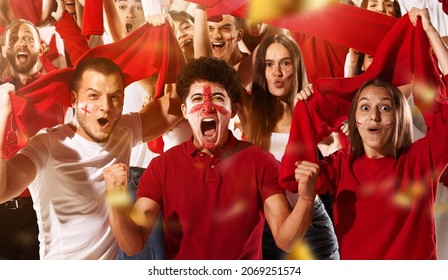 Shouting, Emotional football, soccer fans cheering their team with red scarfs at stadium. Excited fans rejoice goal, supporting favourite players. Concept of sport, emotions, team event, competition.