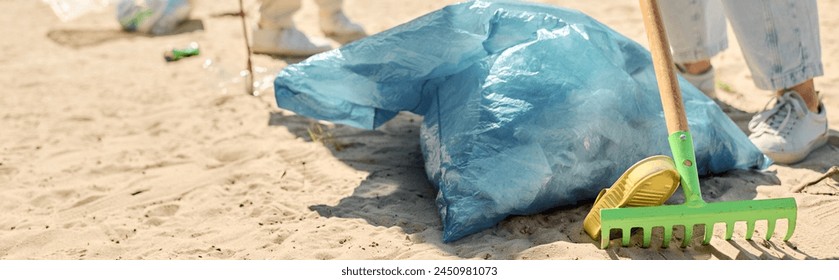 A shovel and a blue bag rest on a sandy beach, symbolizing environmental efforts by a socially active couple cleaning the coast. - Powered by Shutterstock