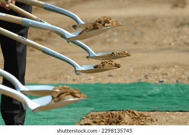 Shovels in the air during a ground breaking ceremony. Shovels filled with dirt.