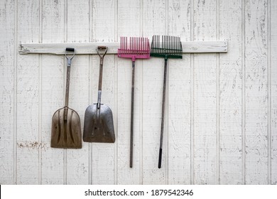Shovels and rakes hung up outside of a stable ready for mucking. - Shutterstock ID 1879542346