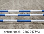 Show jumping poles obstacles, barriers, waiting for riders on show jumping training. Horse obstacle course outdoors summertime. Poles in the sand at equestrian center outdoors