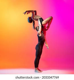 Show, performance. Two dancers, stylish sportive couple dancing contemporary dance on colorful gradient yellow pink background in neon light. Concept of art, creativity, style and fashion, action.