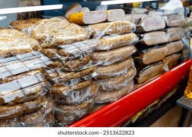 A showcase display case that is filled with an assortment of various types of meats, all wrapped carefully in clear plastic wrap for freshness