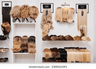 Showcase of natural looking wigs in different colors fixed on the metal wig holders in beauty salon. Row of mannequin heads with variation shades hair on shelf in wig shop
