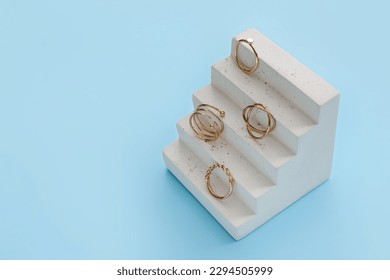 Showcase pedestal with golden rings on blue background - Shutterstock ID 2294505999