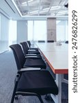 The showcases a modern, professional conference room setting.Room features a large wooden table surrounded by black mesh office chairs, indicating a space designed for meetings or collaborative work. 