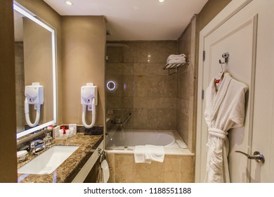 Shower, bathroom in the hotel - bathroom accessories, hairdryer, mirror over the sink and bathrobe on the door, background