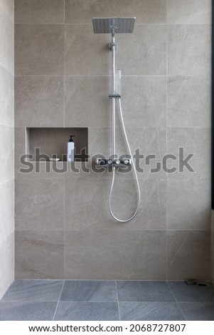 Shower at bathroom. ฺBathroom interior with shower stall and soap Gel bottle. Luxury fully tiled shower with rain head and hand held shower rose.