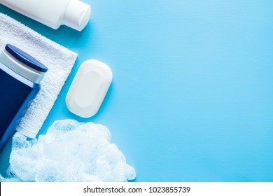 Shower bottles, soap and white towel with wisp on the blue background. Body relax and care products for men. Empty place for text or logo. Top view.