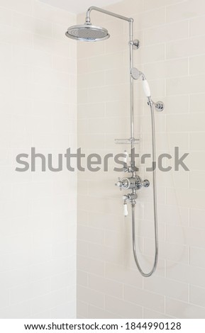 Shower with fixed rainfall shower head, slide rail and handset in a new, luxury bathroom, UK