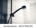 Shower head. Dark dramatic scary light. Cold water running in bathroom. Public washroom in hostel, gym or bad hotel. Hot flow. Black faucet. Emotional, horror or dirty. Wash room for bath.