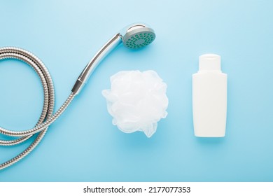 Shower head, white plastic bottle and soft wisp on light blue table background. Pastel color. Things for body washing. Closeup.
