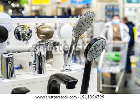 Shower heads. An assortment of plumbing fixtures on the counter in a chain store against the background of buyers. Foreground. Selective focus
