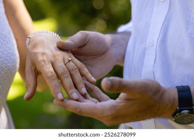 Showing engagement ring, senior bride and groom holding hands outdoors, at outdoor wedding. Romance, love, celebration, commitment, relationship, happiness - Powered by Shutterstock