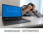 showing error blue screen on the Laptop against the background of an angry upset man clutching his head