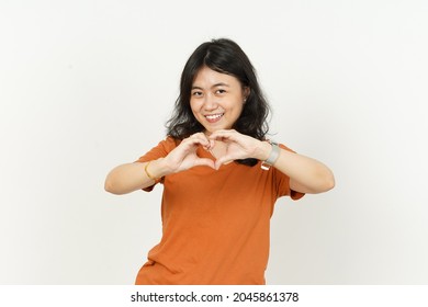 Showing Heart Shape Hand Sign Of Beautiful Asian Woman Wearing Orange T-shirt Isolated On White Background