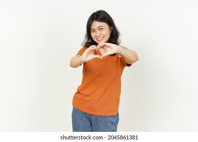 Showing Heart Shape Hand Sign Of Beautiful Asian Woman Wearing Orange T-shirt Isolated On White Background