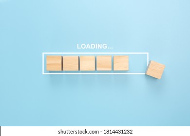 Showing loading bar with wood cube on blue background. Wooden blocks with the word LOADING in loading bar progress. Concept loading.