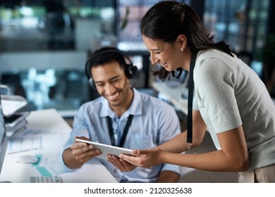 Showing The New Rep The Ropes. Shot Of A Young Man And Woman Using A Digital Tablet While Working In A Call Centre.