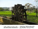 Showing a scene of a dilapidated water wheel on a small creek, likely broken down long ago. It now serves as a leisurely attraction for people passing by.